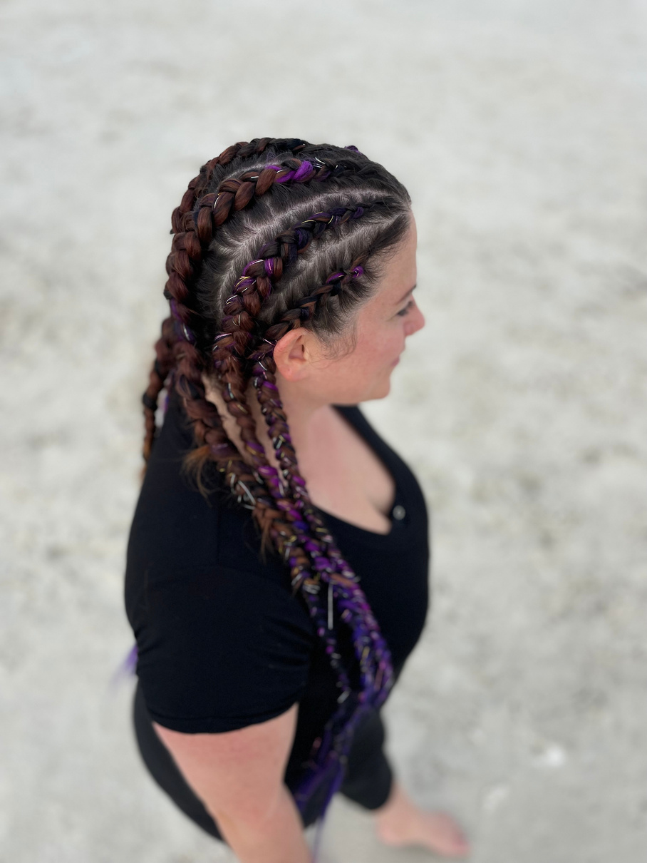 a person with purple and black braids on their head beachside in daytona beach